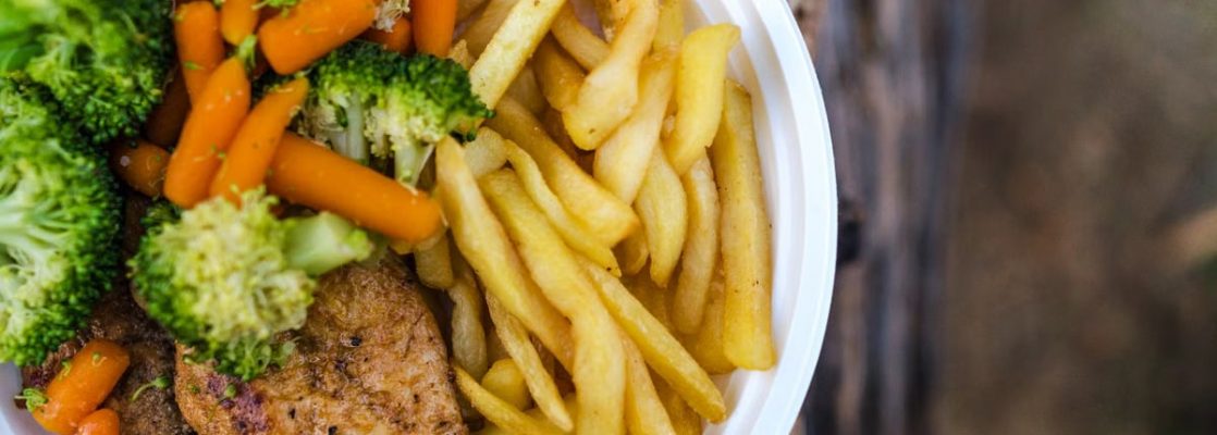 Delicious chicken dinner with broccoli, carrots, and fries on a plate.