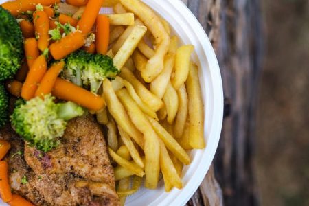 Delicious chicken dinner with broccoli, carrots, and fries on a plate.