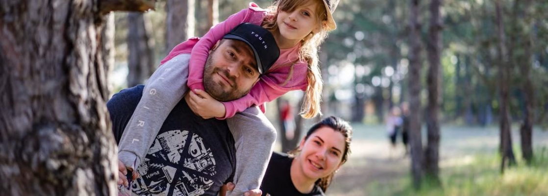 A joyful family enjoying a playful day in a sunlit forest park, capturing the essence of togetherness.